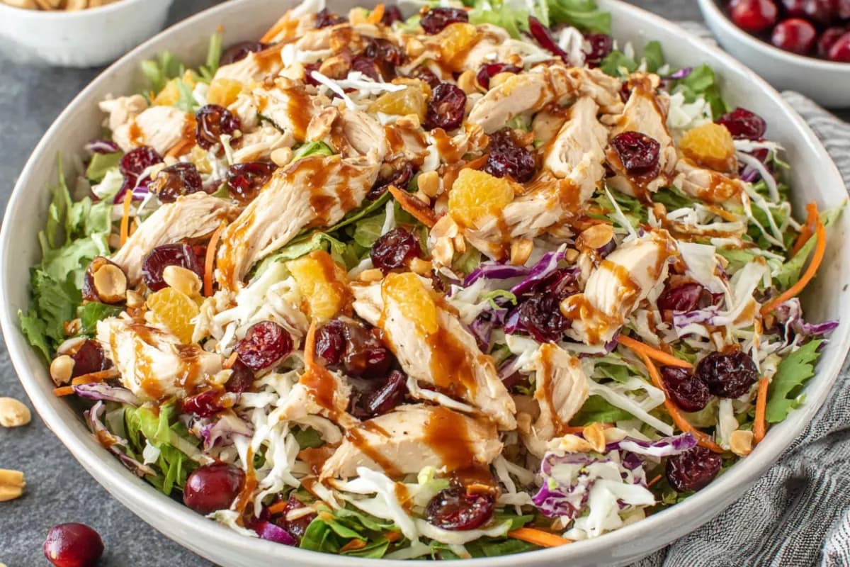 Asian Chicken Cranberry Salad in bowl with mandarin oranges, shredded cabbage, and cranberries
