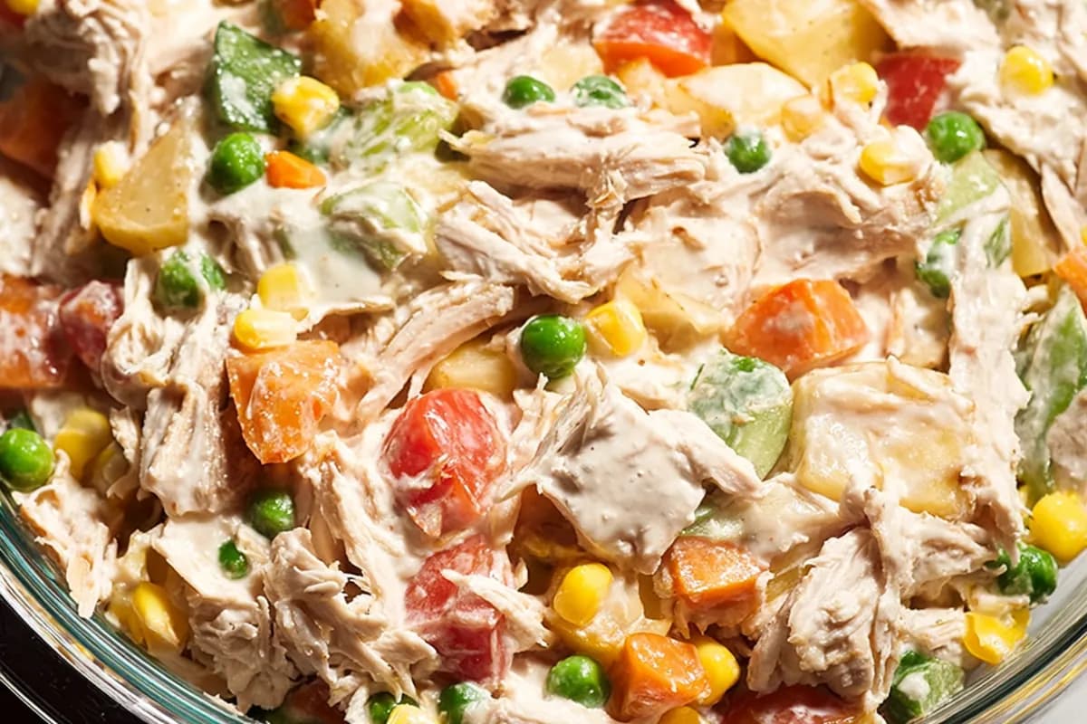 Mexican Chicken Salad in a glass bowl with creamy dressing, corn, peas, and carrots