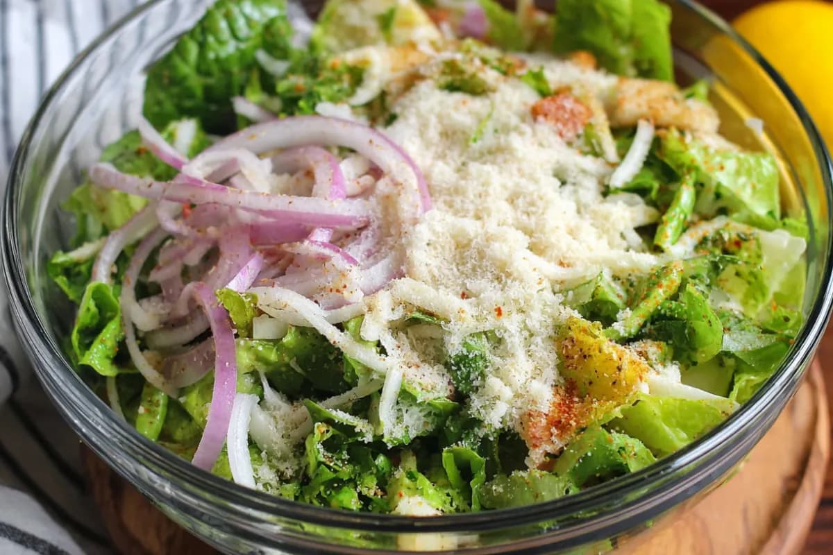 Bowl of parmesan chopped salad with romaine lettuce, red onions, grated parmesan cheese, and seasonings