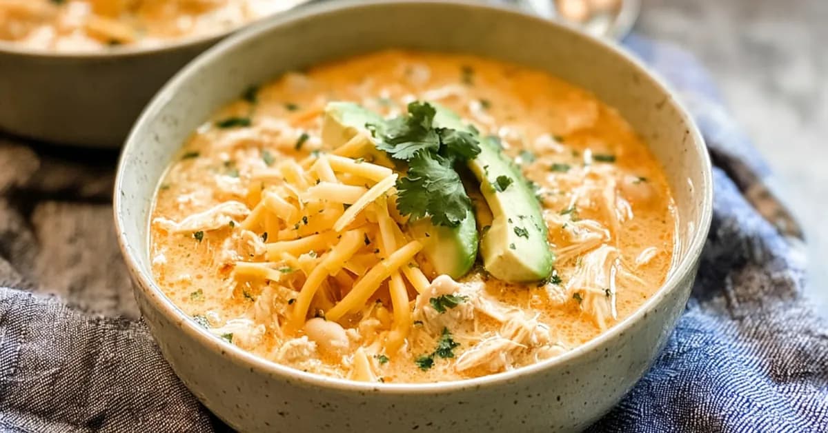 Creamy white chicken chili topped with shredded cheese, avocado slices, and fresh cilantro in a bowl
