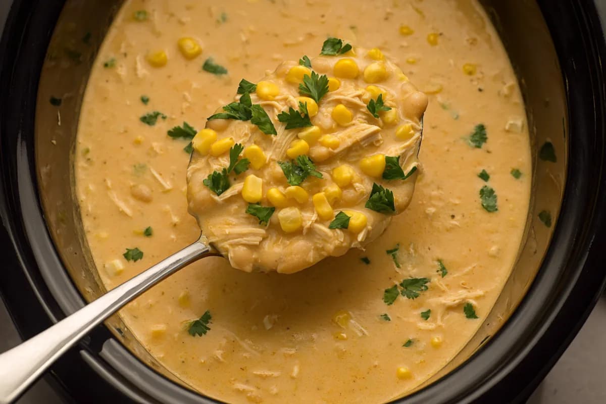 Creamy white chicken chili crockpot recipe with corn and shredded chicken, served in a slow cooker