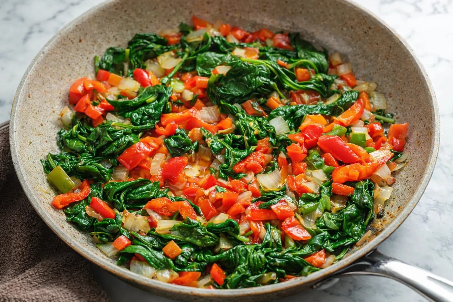 sautéed bell peppers onions and spinach in skillet for breakfast enchiladas filling