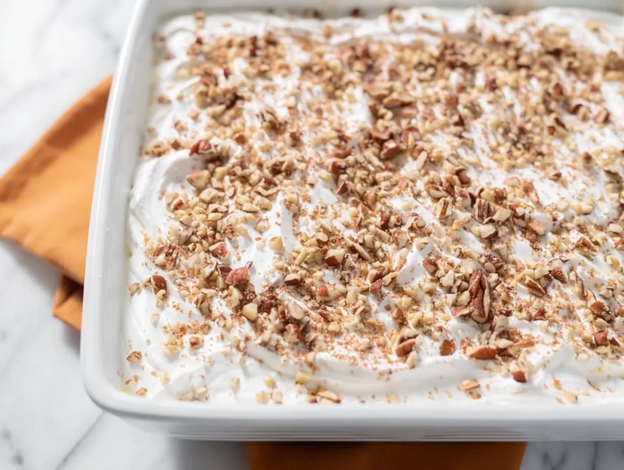 Top view of the finished pumpkin delight dessert layered with whipped topping and chopped pecans, ready to chill.